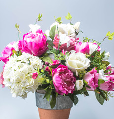 Closeup bouquet of artificial flowers. Ornamental bouquet in red bucket on white background. Vintage bloom decoration.