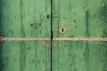 Closed up of aged vintage green door with keyhole as background