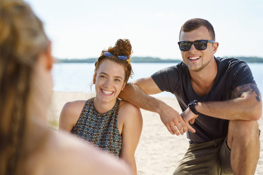 Happy young couple relaxing with friends by the ocean