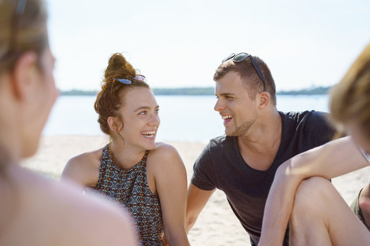 Laughing young couple relaxing with friends at the beach