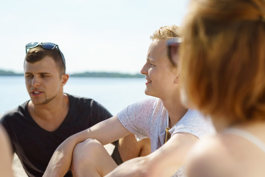 Young man talking to a group of friends on the beach