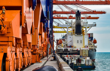 A large container vessel attaching to a pier at an industrial port. Cargo container terminal. Port...