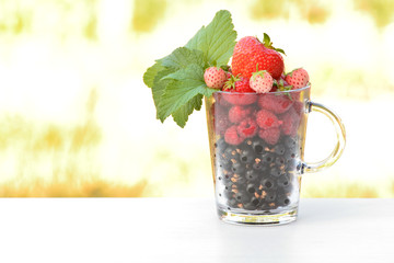 Freshly washed berries ( Strawberry, currant, raspberry) in a transparent glass. High-key shooting.