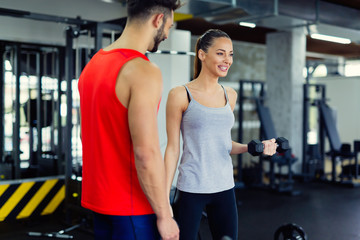 Young adult woman working out in gym with trainer
