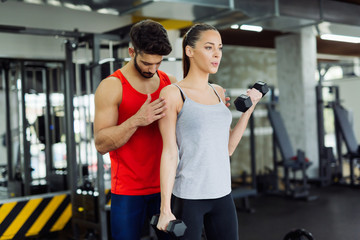 Young adult woman working out in gym with trainer