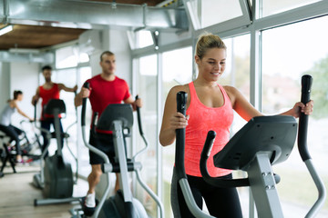 People doing on elliptical trainer in gym - obrazy, fototapety, plakaty