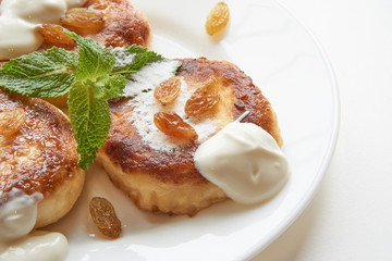 close up shot of pancakes on white plate with raisins and mint