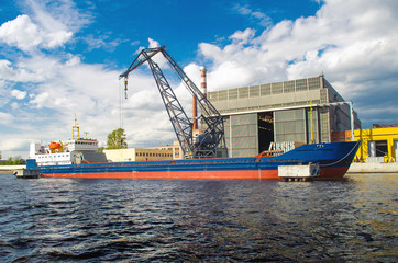 Cargo ship in the port and cargo crane on the pier.