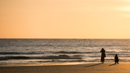 Fototapeta na wymiar silhouette woman take photo on beach at sunset time.