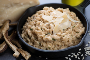 Close-up of a frying pan with porcini mushrooms risotto topped with parmesan cheese, selective focus