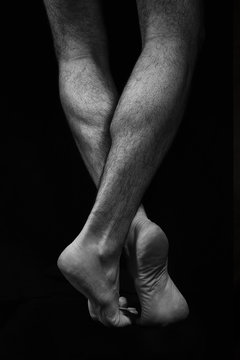 Naked muscular male legs on a black background