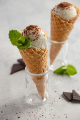 Vanilla ice cream in waffle cone on grey concrete background, selective focus