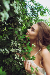Pretty woman enjoying smell flowers. Portrait of young beautiful woman posing among blooming trees