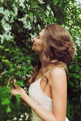 Pretty woman enjoying smell flowers. Portrait of young beautiful woman posing among blooming trees