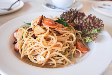 Spicy spaghetti with sausage,and dried chili closeup on white plate