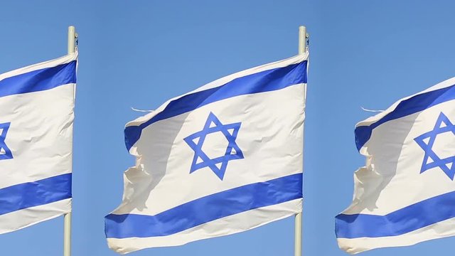 Three flags of Israel flapping on masts in a strong wind