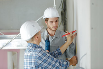 specialist and assistant working with wall in new building