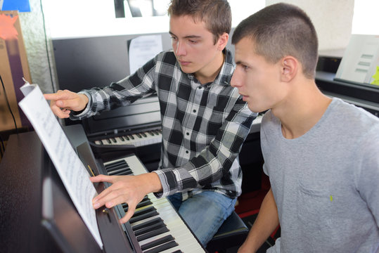 young men learning to play piano