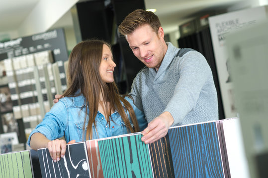 positive couple looking at flooring in interior store
