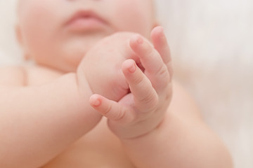 Newborn hands detail closeup. Lying on the bed and folding the hands