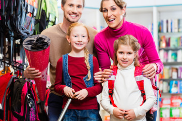 Family with two kids choosing school satchel in store
