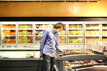 Man shopping in supermarket, reading product information