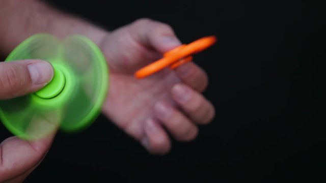 Footage of a person playing with two fidget spinners, isolated on a black background...