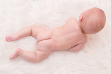 Νaked infant crawling on his belly on white fluffy blanket - 161898384