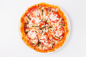 Pizza with tomato, mushrooms, bell peppers on a white plate on a light background  (close top view)