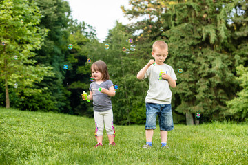 Fototapeta premium Kids on a meadow are blowing bubbles
