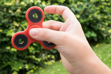 Boy hand holding a red fidget spinner toy