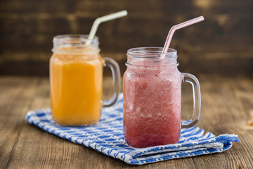 two glasses of smoothies from strawberries, raspberries, banana and carrot juice, lemon, honey , close up