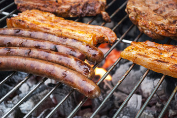 Barbecue im Sommer mit gegrillten Würstchen und Fleisch auf Holzkohlegrill 
