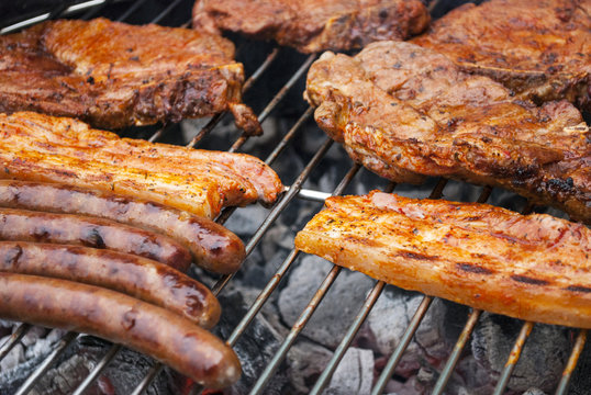Barbecue im Sommer mit gegrillten Würstchen und Fleisch auf Holzkohlegrill 