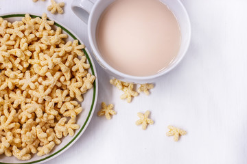 a healthy Breakfast of corn flakes, milk and tea on a white table