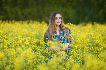 Naklejka na ściany i meble Attractive young blonde woman in blue plaid shirt straw hat enjoying her time on bright colorful blossoming yellow green meadow hard noon sun.