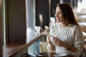Beautiful woman drinking coffee in restaurant alone