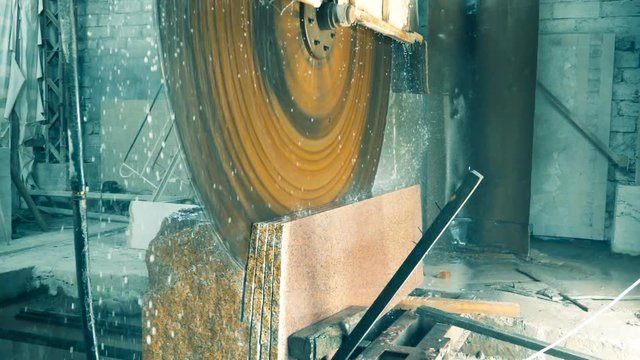 Circular saw cuts a granite block, slow motion