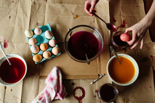 High angle view of child dipping egg into red liquid 