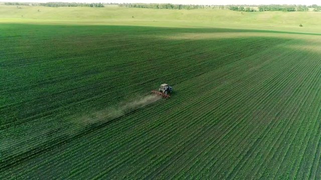 A tractor is plowing large fields of potatoes