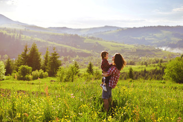 Mom and baby stand and watch the sunset in the mountains