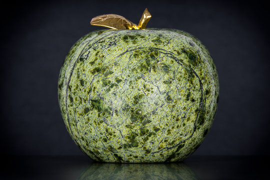 Ein gr&uuml;ner Apfel aus Serpentin Gestein mit goldenem Stiel und Blatt