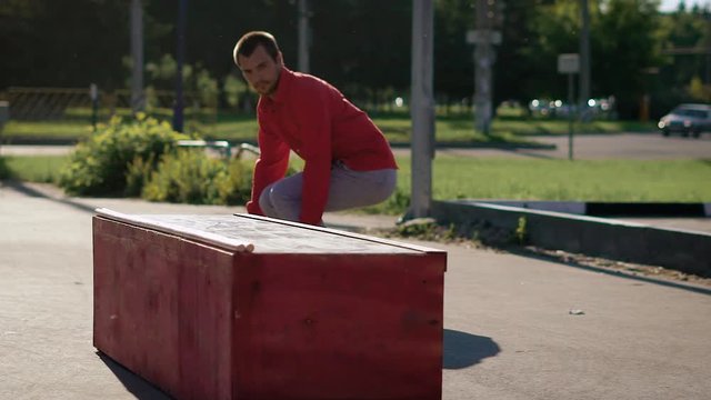 An adult skateboarder who loves his hobby, jumps on a fanbox, then moves off it on a board in a street skatepark in the summer