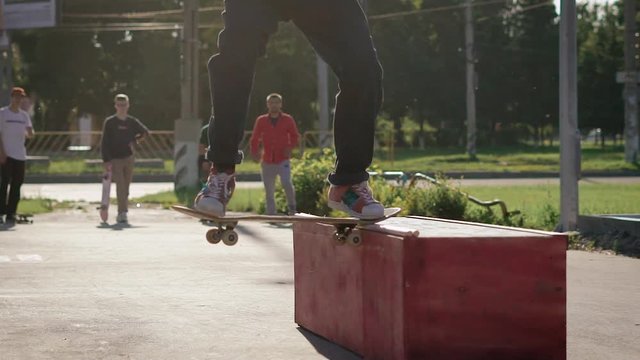 An adult teenager in street clothes tries to skate on a skateboard on a big fanbox, but the skateboarder fails to perform the trick