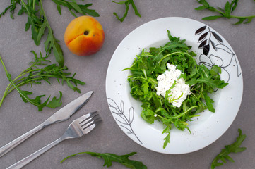 Salad with green arugula plant and cottage cheese isolated. Rustic style. Gray stone background. Top view. Close-up