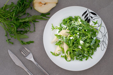 Salad with green arugula plant, pear and cottage cheese isolated. Rustic style. Gray stone background. Close-up. Top view