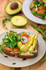 Homemade sandwich with avocado, salmon, arugula and humus. Rustic style. Gray stone background. Close-up. Top view