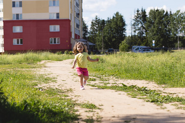 The little girl is running along the road
