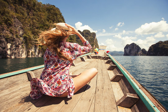 Beautiful girl traveling by boat in mountain tropical lake, the wind fluttering hair