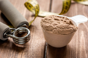 nutrition for workout with protein cocktail powder, measure tape and bars on wooden background close up